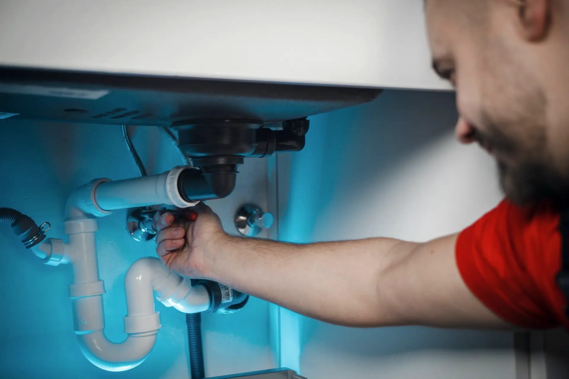 Plumber repairing pipes under a basin