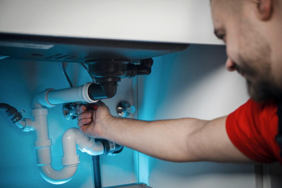 Plumber repairing pipes under a basin