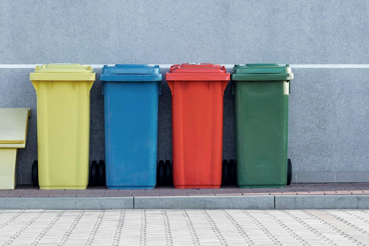 Colour-coded recycling bins against a wall