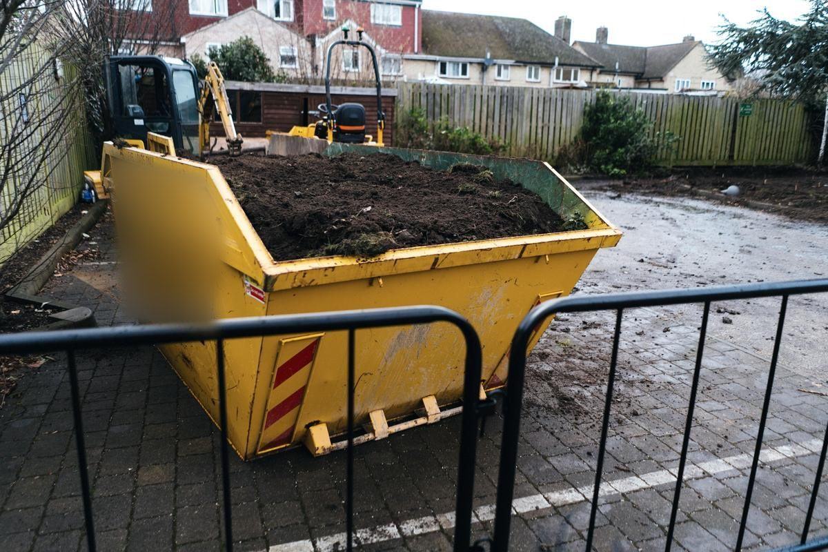 Yellow skip filled with soil on a residential building site