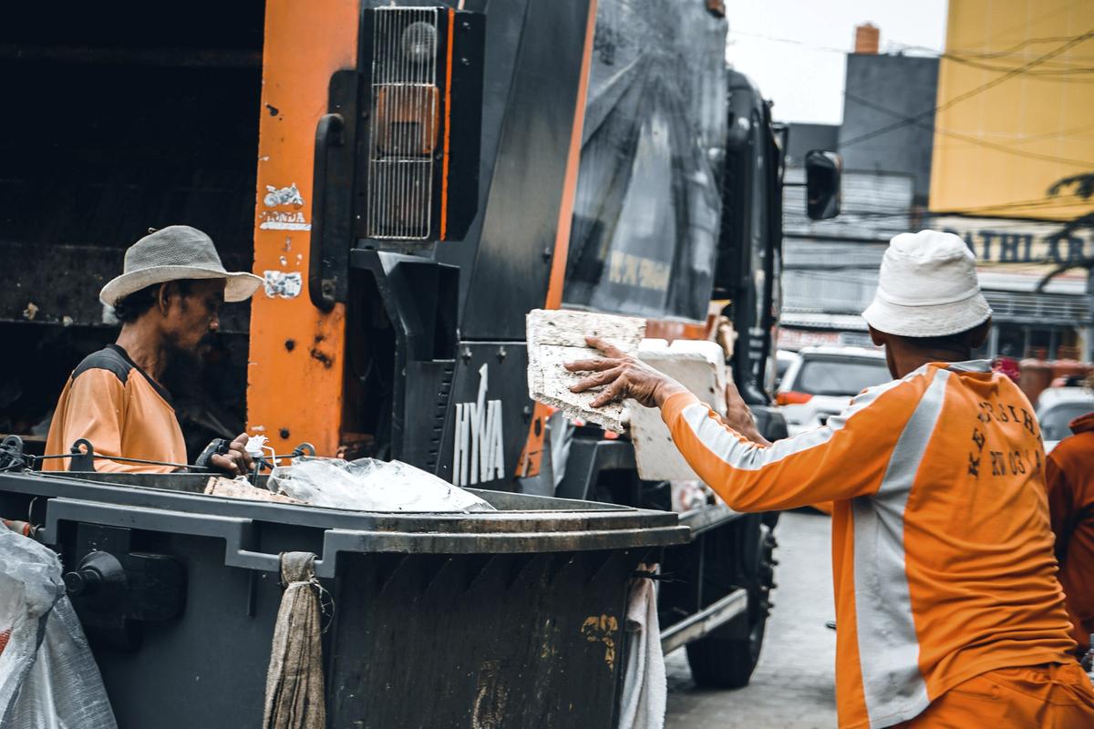 Workers loading waste into a collection truck